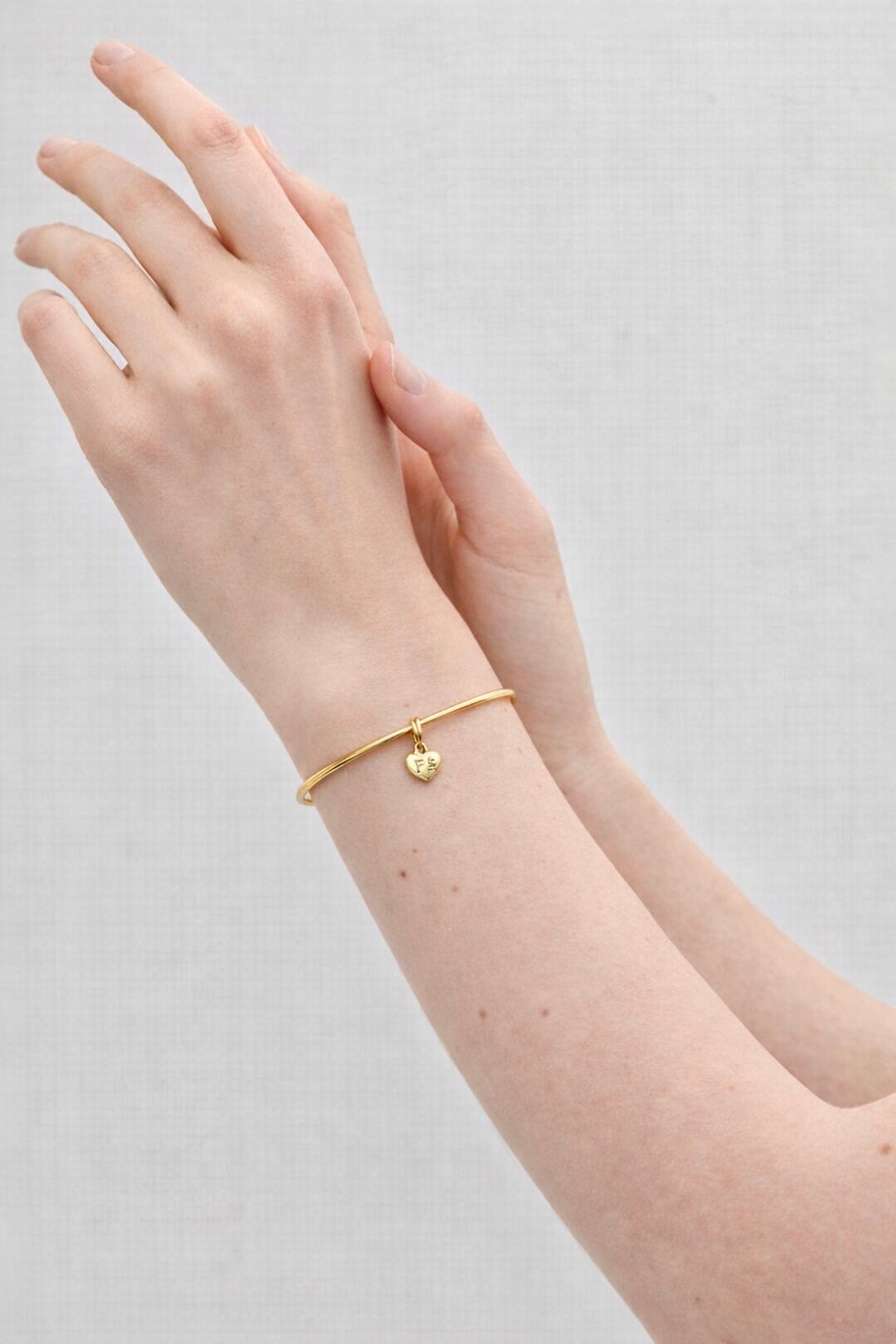 Pulseira Fé semijoia banhada a ouro com pingente coração gravado e aro delicado – Liáh Joia Cristã
