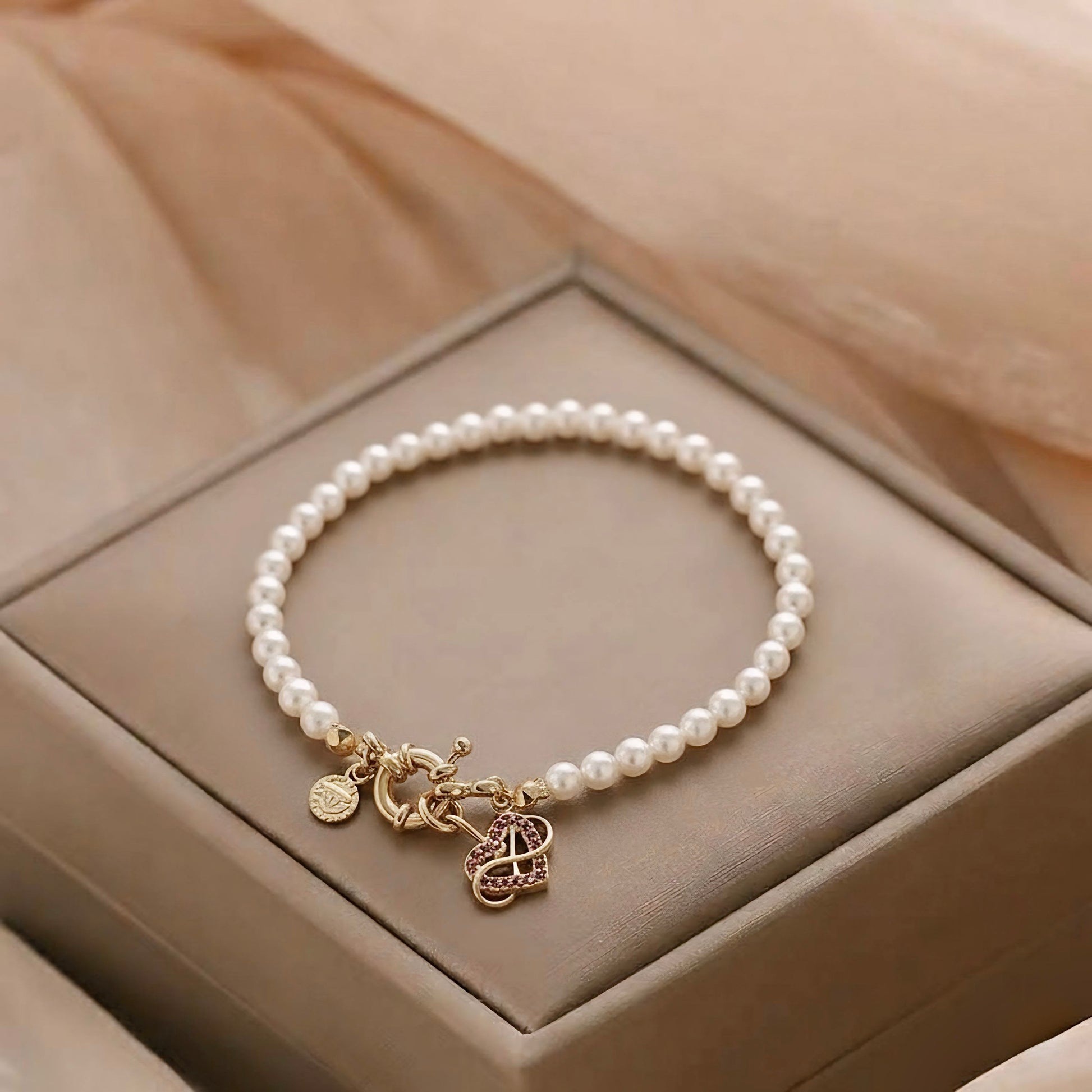 Pulseira feminina de pérolas com fecho dourado e pingente coração com pedras rosas, semijoia banhada a ouro – Liah Joia Cristã